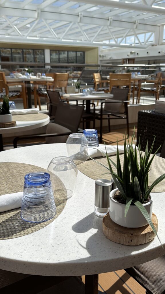 Sunlit tables in the Viking Mars Wintergarden beneath a white geometric canopy.