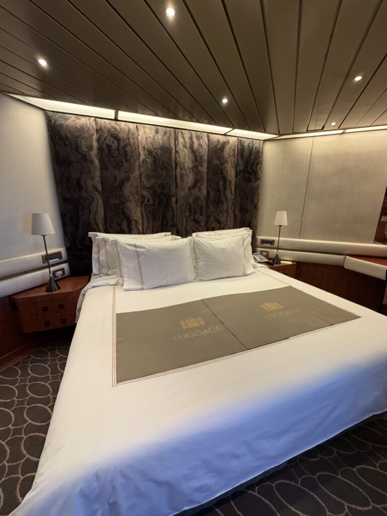 Holland America Volendam stateroom with queen bed, dark wood furnishings and upholstered headboard