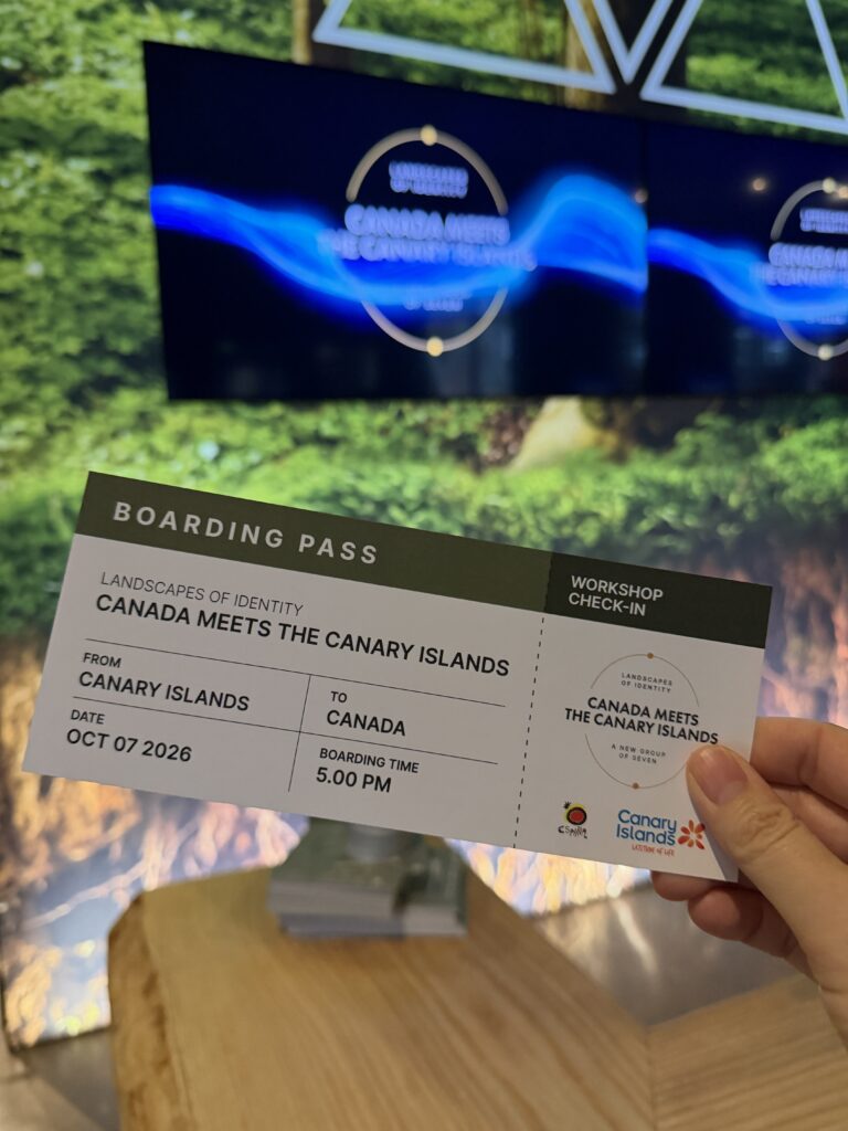 Hand holding a Canada Meets the Canary Islands event boarding pass in Toronto, with Canary Islands tourism branding in the background.