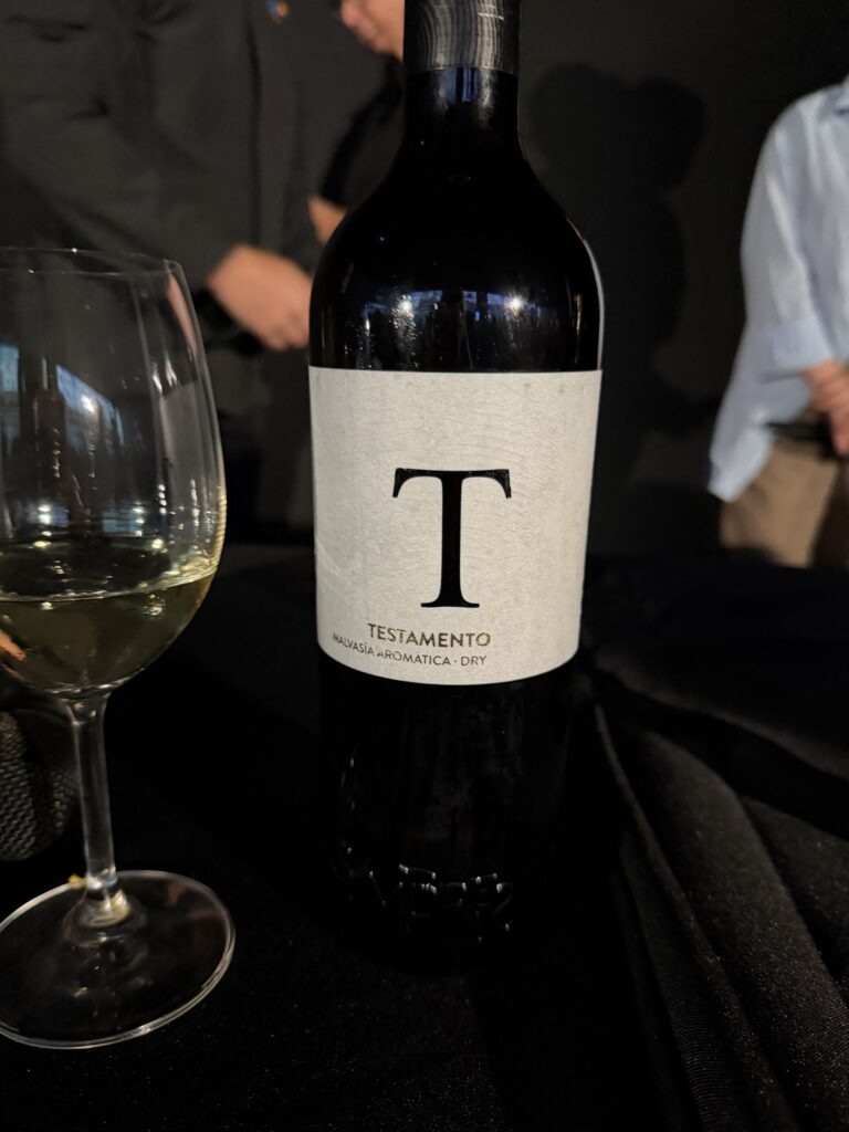 Bottle of Testamento Malvasía Aromática dry white wine from Tenerife, Canary Islands, beside an empty wine glass.